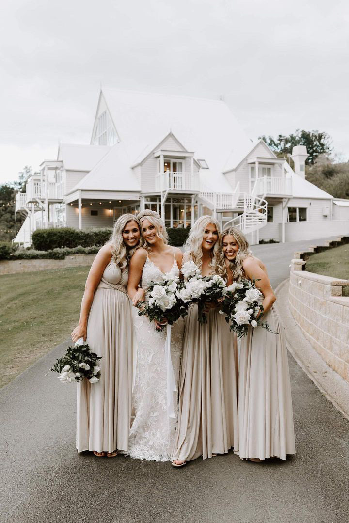 Four women in Champagne Infinity Gown multiway bridesmaid dresses holding bouquets