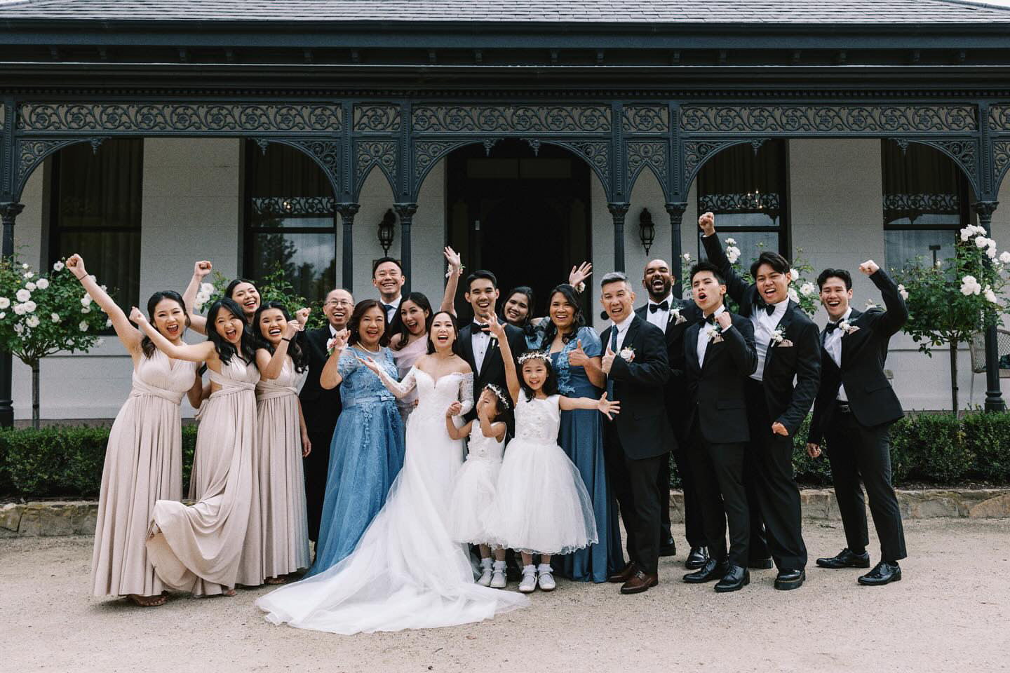 Wedding celebration with a large group in front of an elegant building wearing Champagne Infinity Gown, a versatile convertible dress Australia