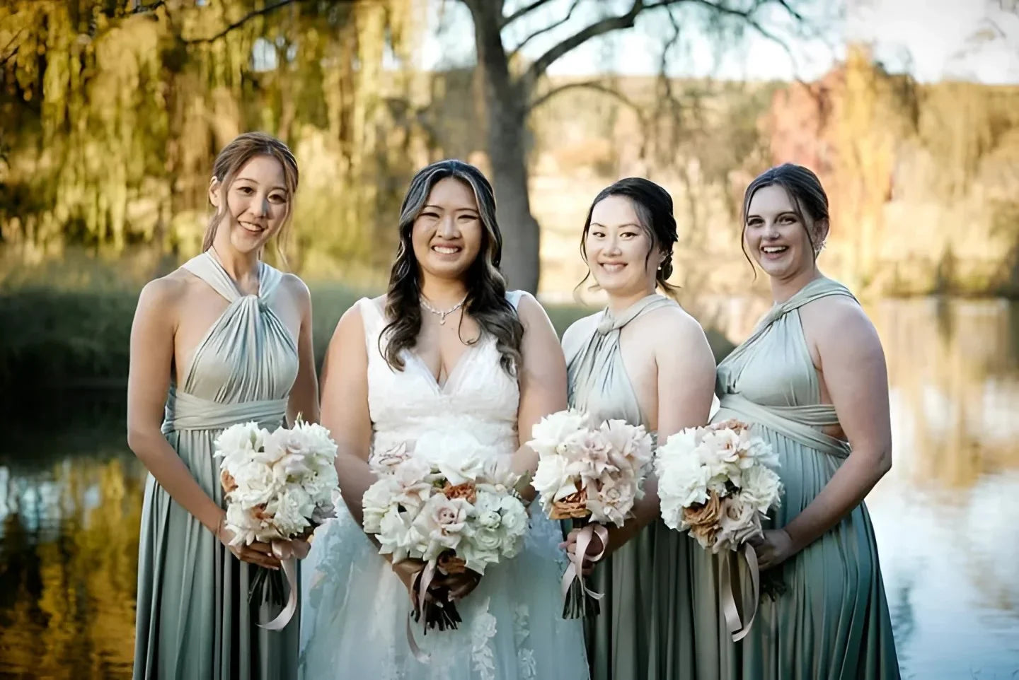 Four women in wedding attire holding bouquets wearing the Eucalyptus Infinity Gown, a versatile green bridesmaid dress