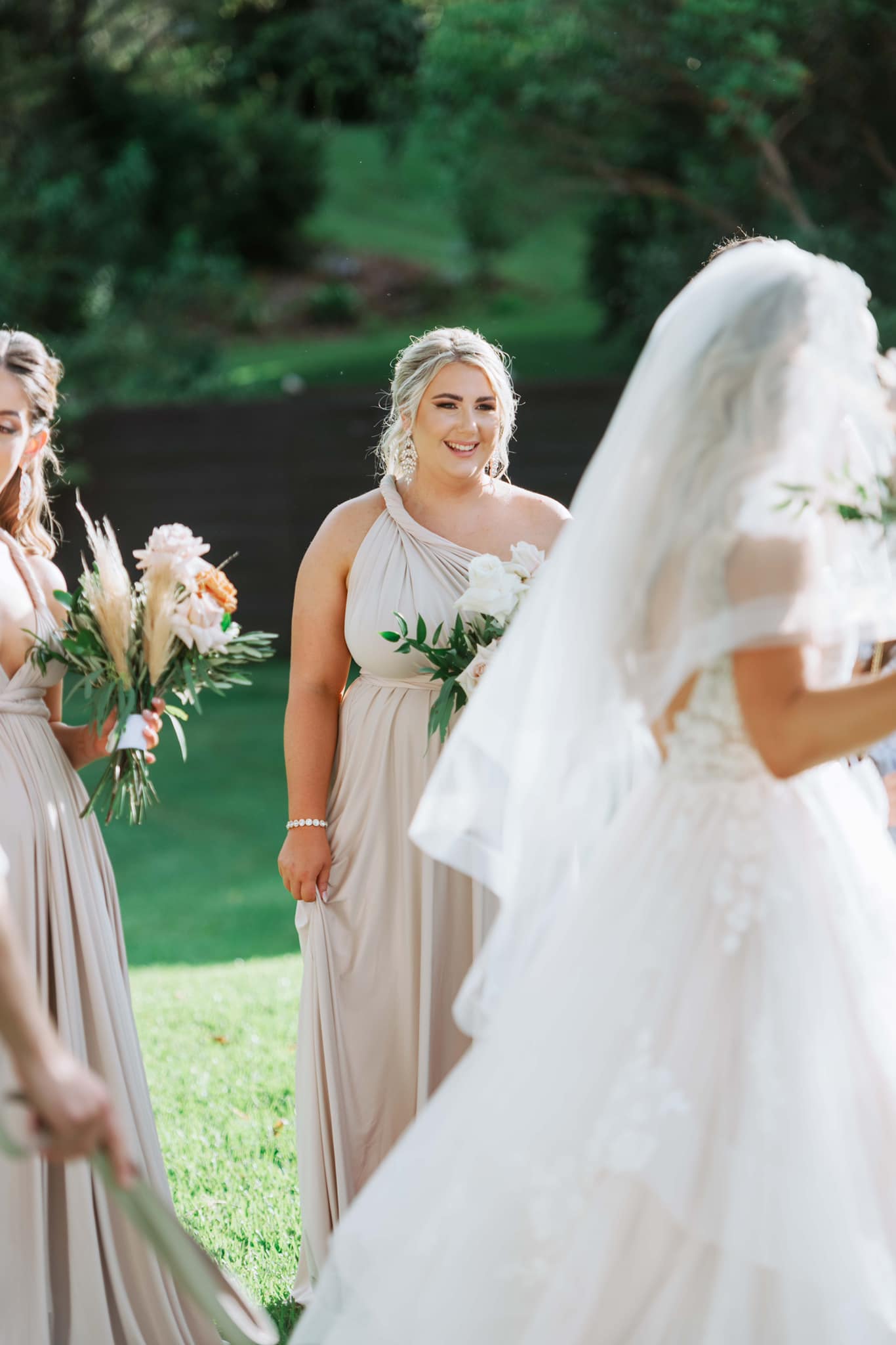 Three women in champagne bridesmaid gowns at an outdoor event wearing Champagne Infinity Gown