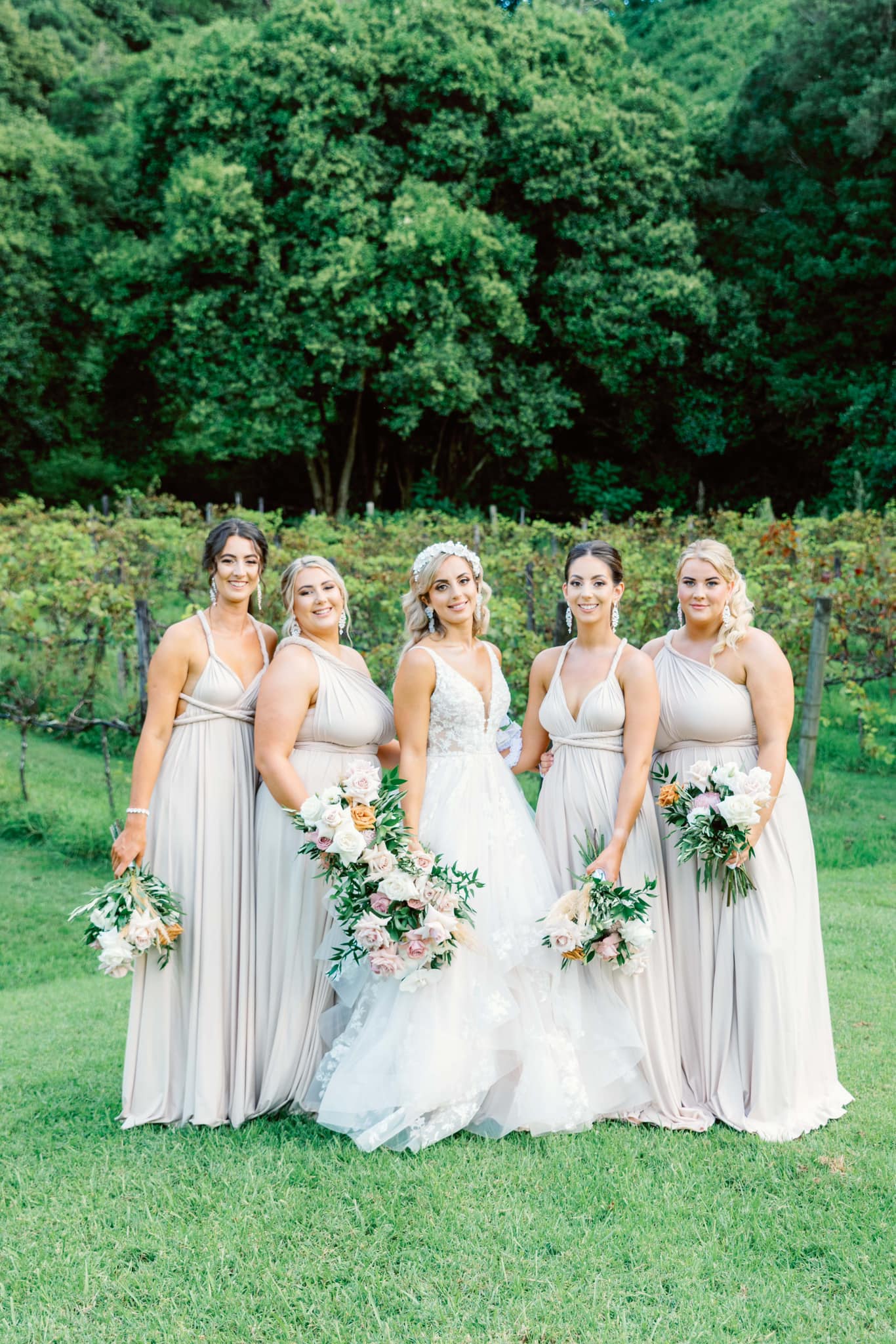 Bride in a white gown with bridesmaids in light-colored multiway bridesmaid dresses featuring champagne bridesmaid gown styles in Australia