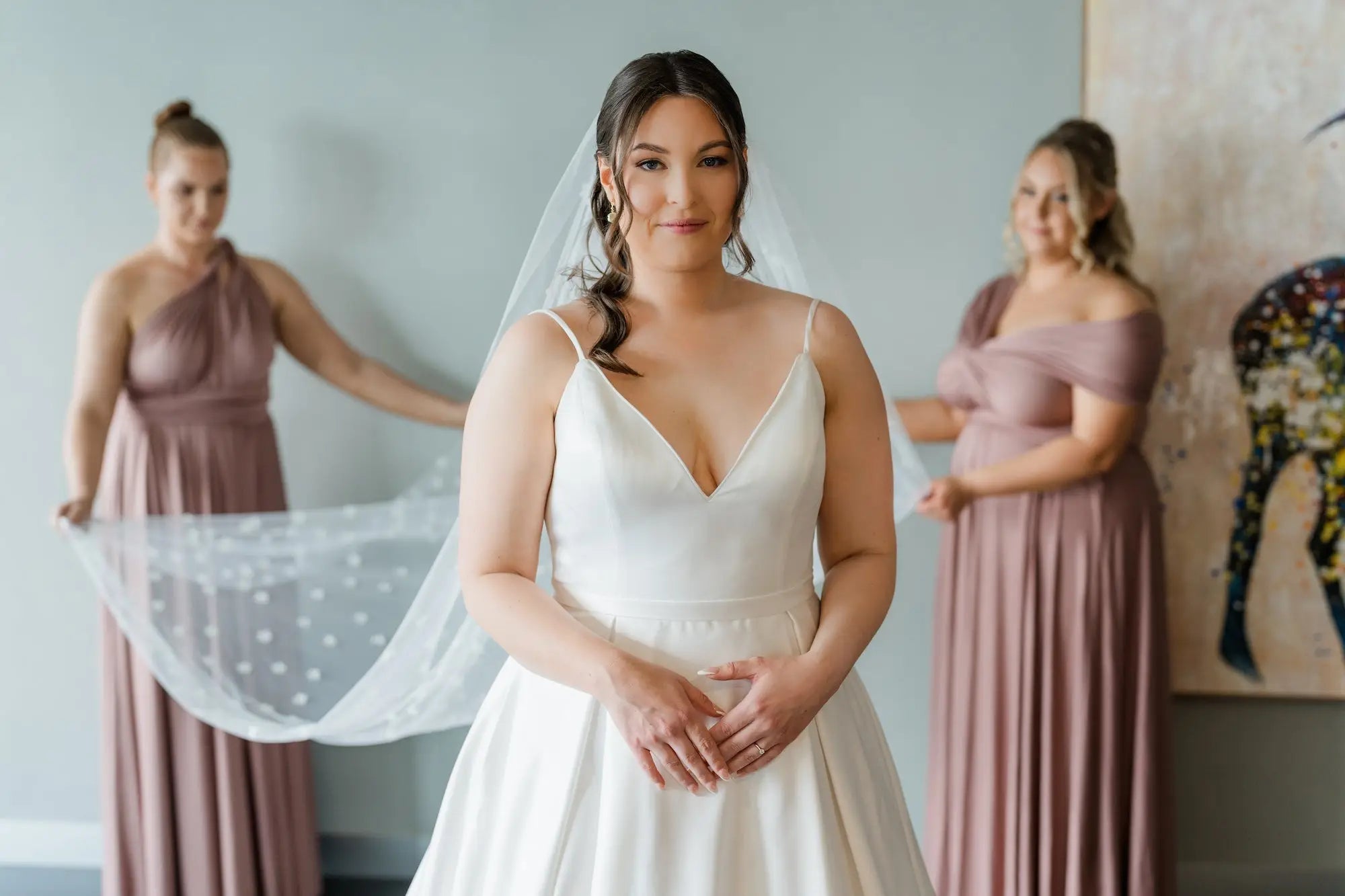 Young woman in wedding gown with bridesmaids in mauve infinity bridesmaid dresses