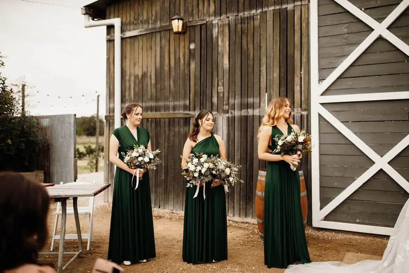 Three bridesmaids in dark green infinity dresses holding bouquets for Classic Emerald article