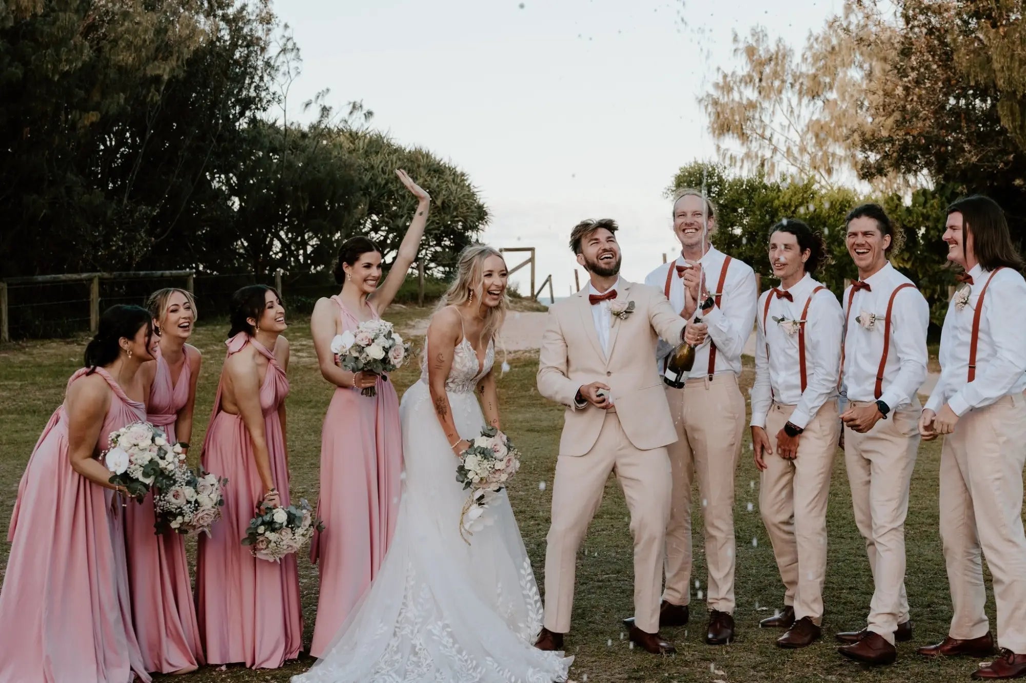 Wedding celebration with bride and groom holding champagne, featuring infinity dress Australia