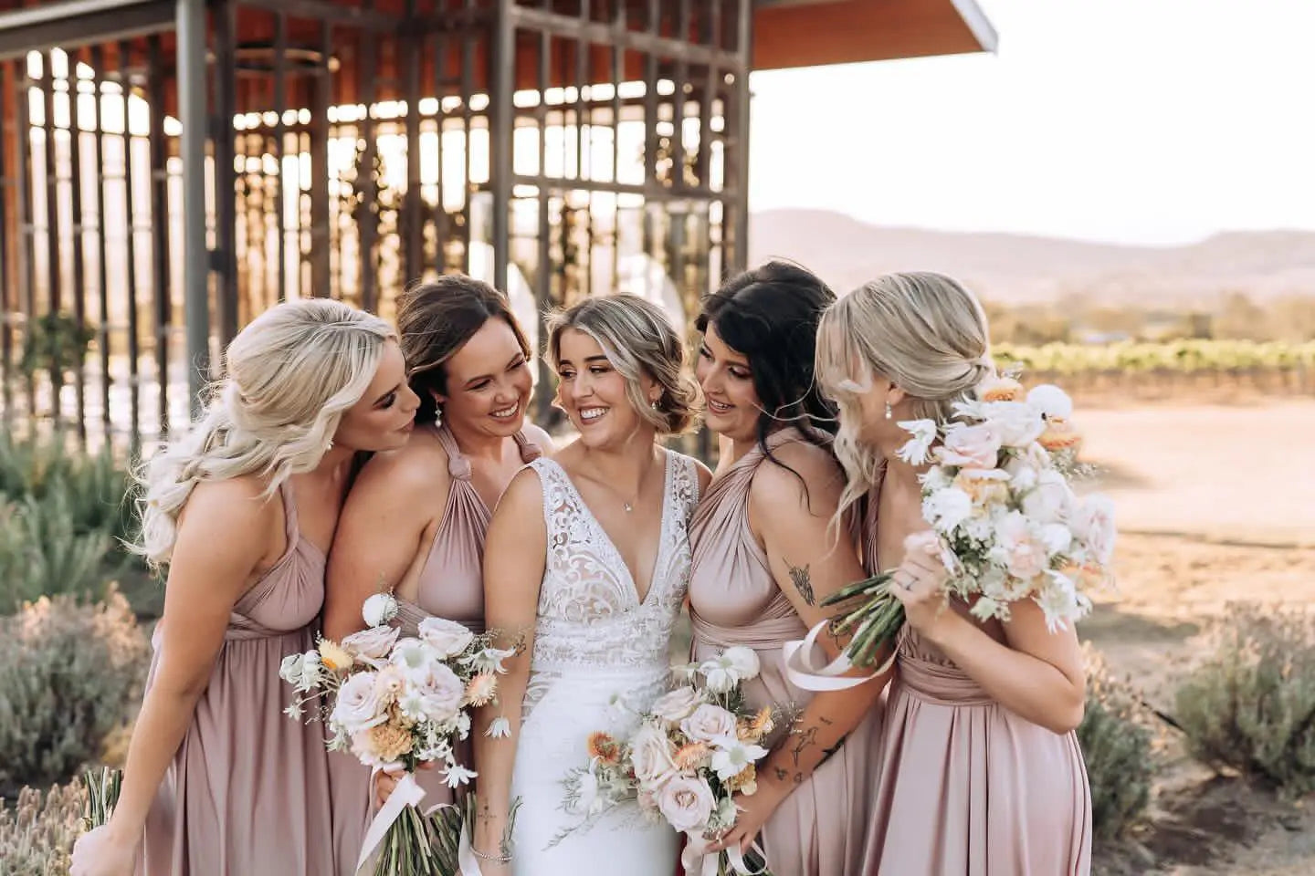 Bride and bridesmaids in matching infinity dresses with floral bouquets at Georgia and Shane wedding