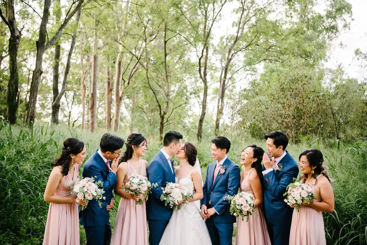 Wedding party outdoors with bride in white gown, groom in blue suit, bridesmaids in pink, infinity bridesmaid dress in Australia