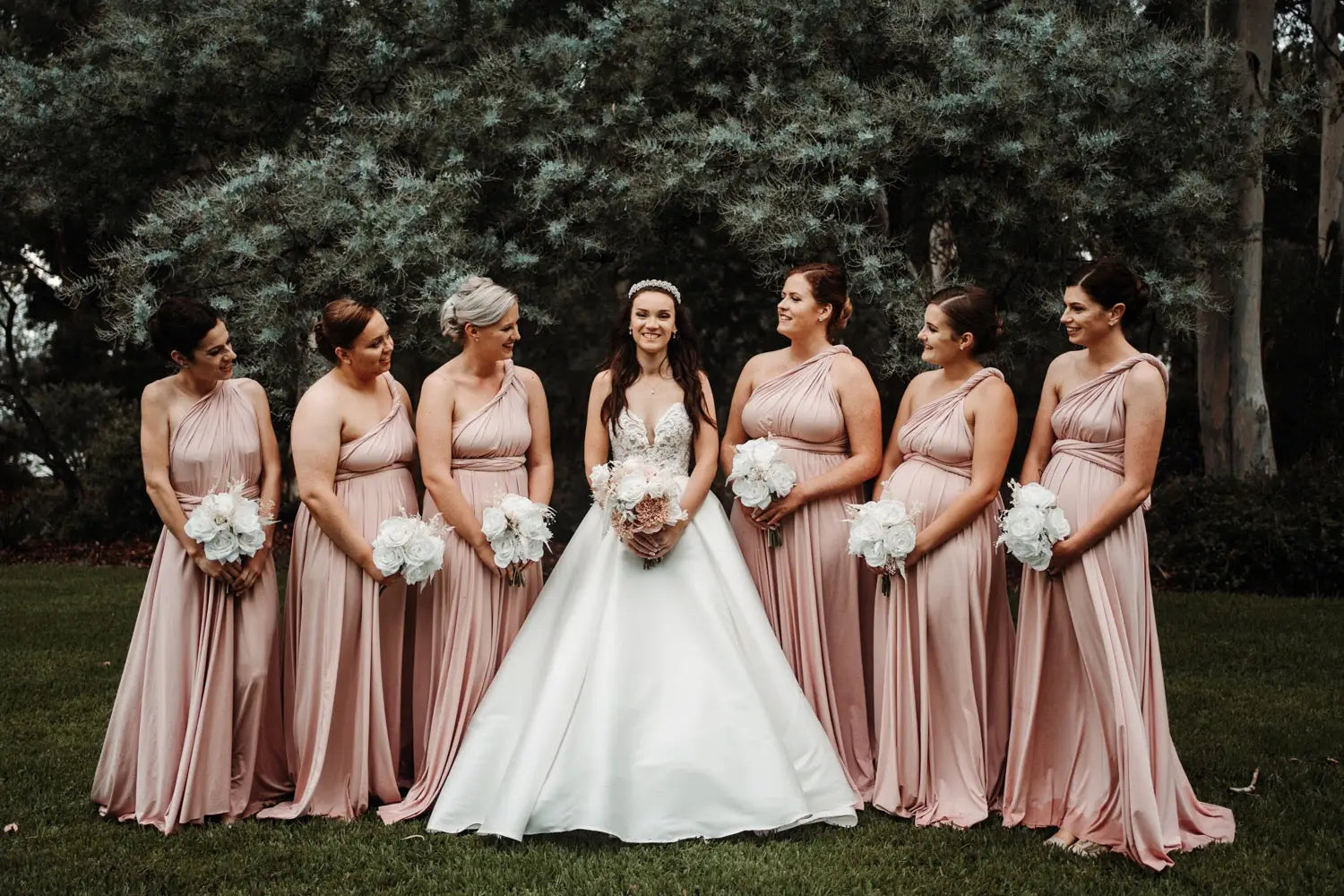 Bride in white gown with six bridesmaids in pink infinity bridesmaid dresses in Jennifer and Jamie