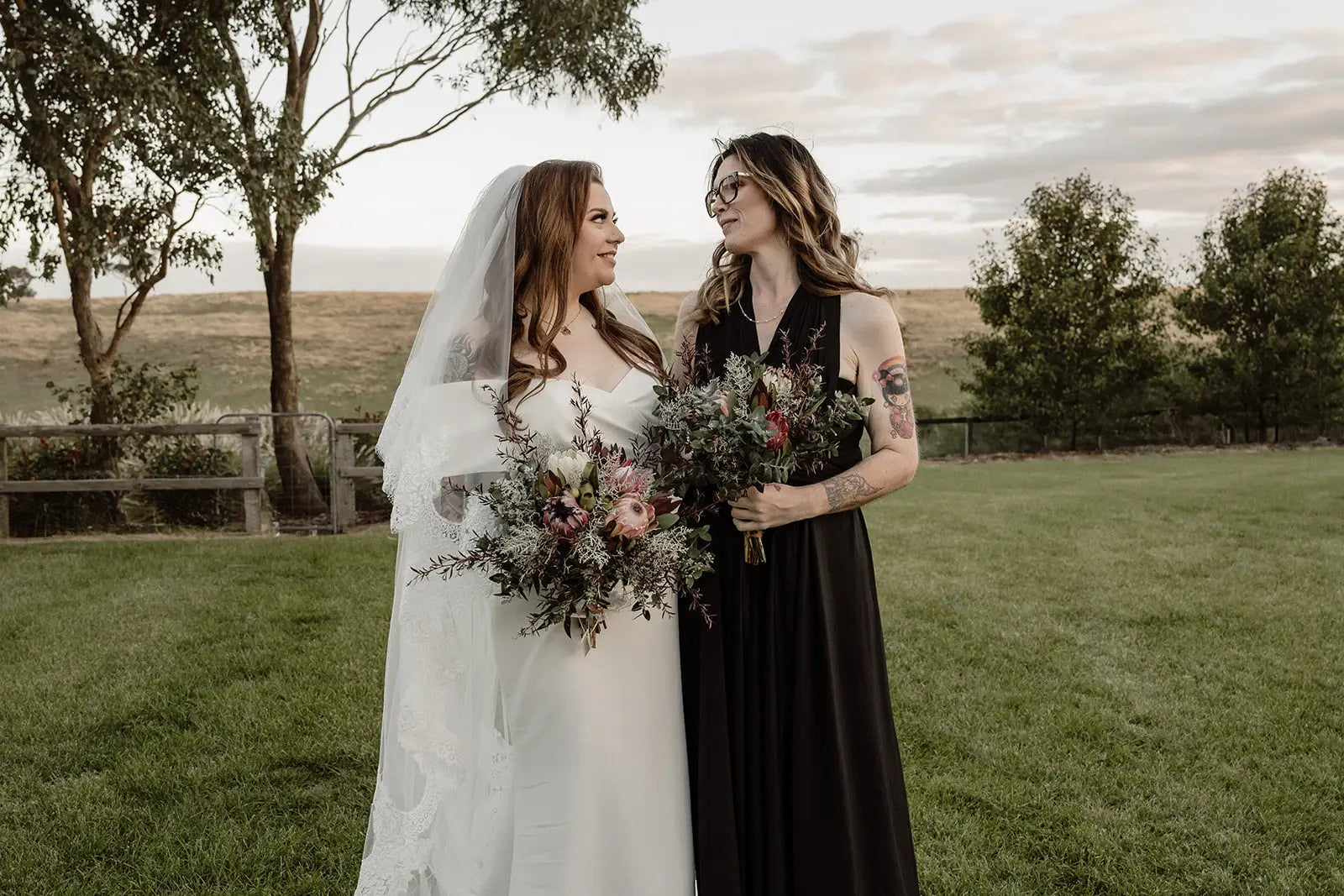Two women in wedding attire holding bouquets wearing infinity dresses Australia for Kate and Kyle