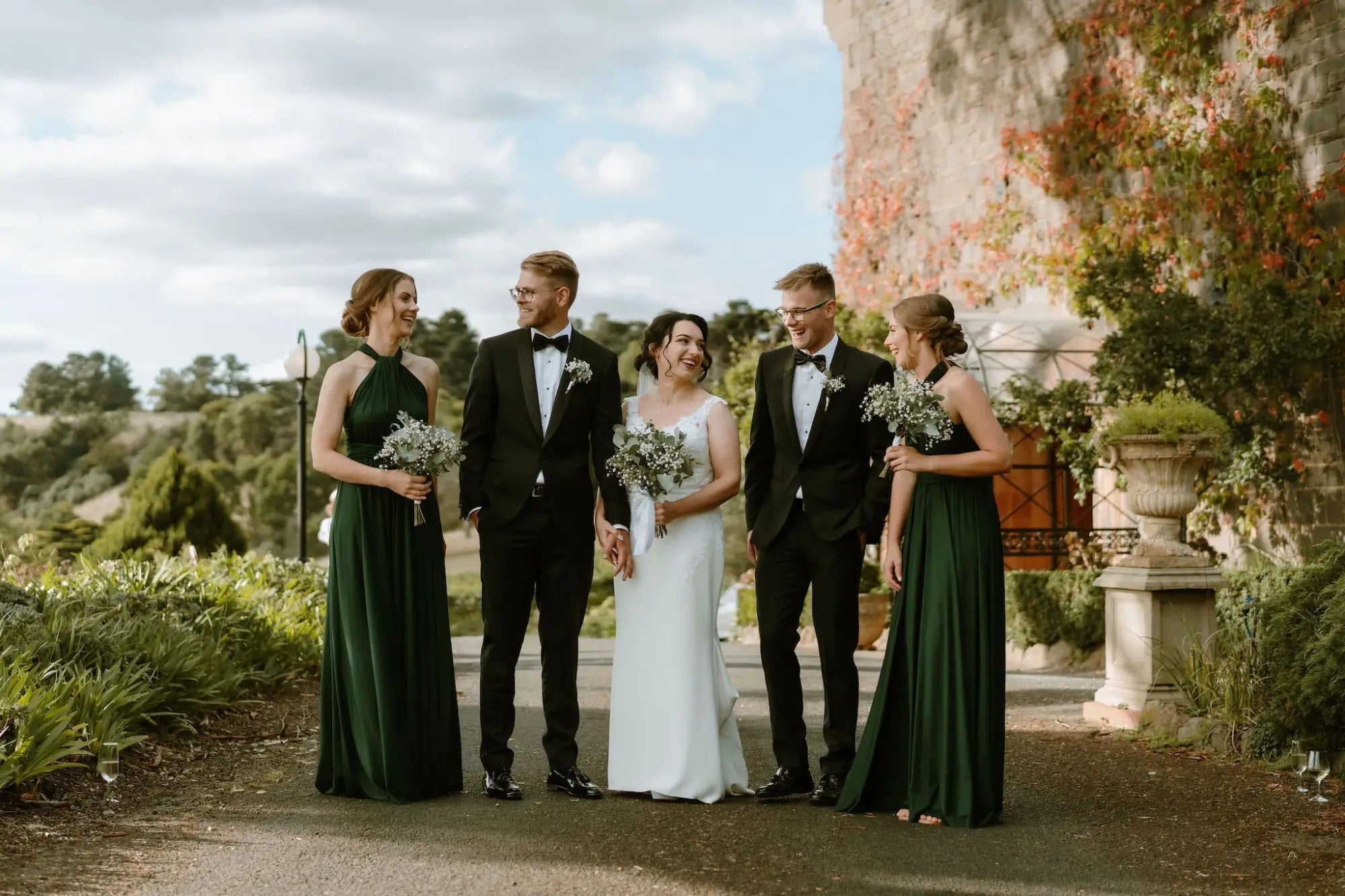 Wedding party with bride and groom in formal attire holding bouquets, featuring infinity dress Australia