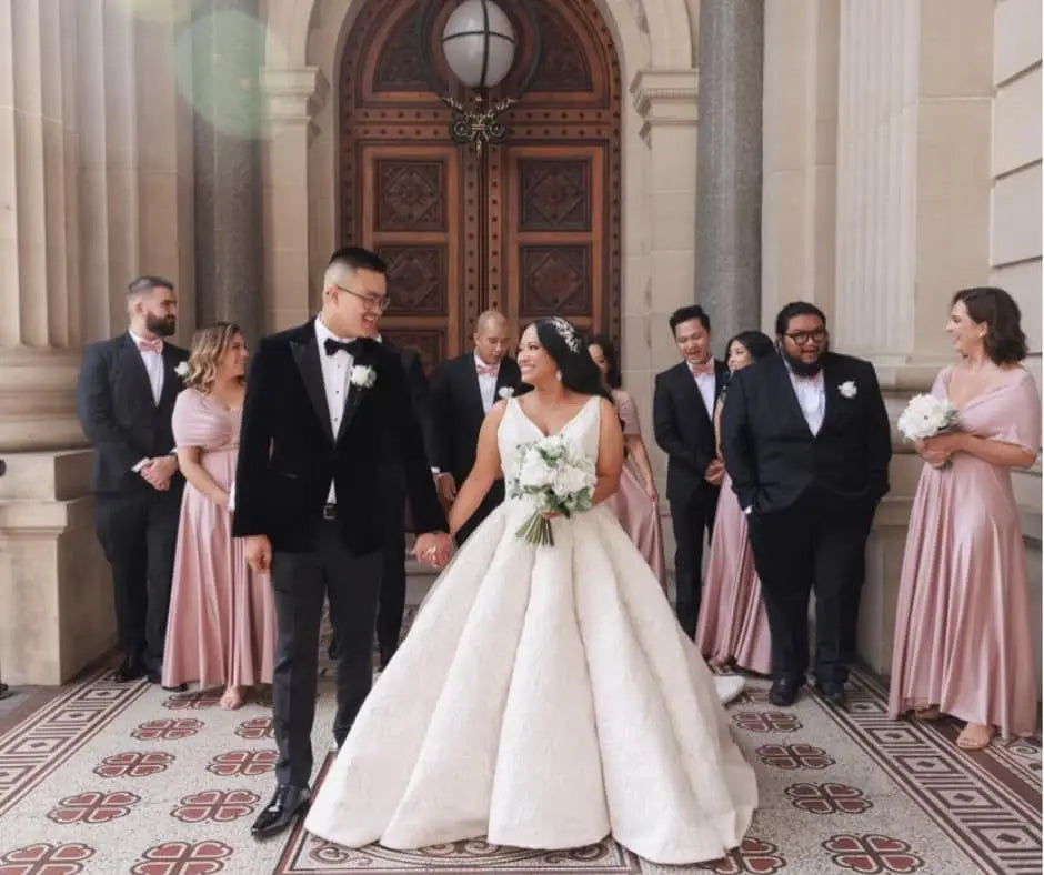 Wedding party with bride and groom holding hands wearing infinity dress Australia