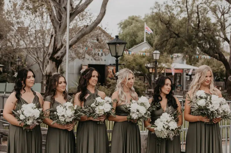 Six bridesmaids in matching olive green infinity bridesmaid dresses with white floral bouquets