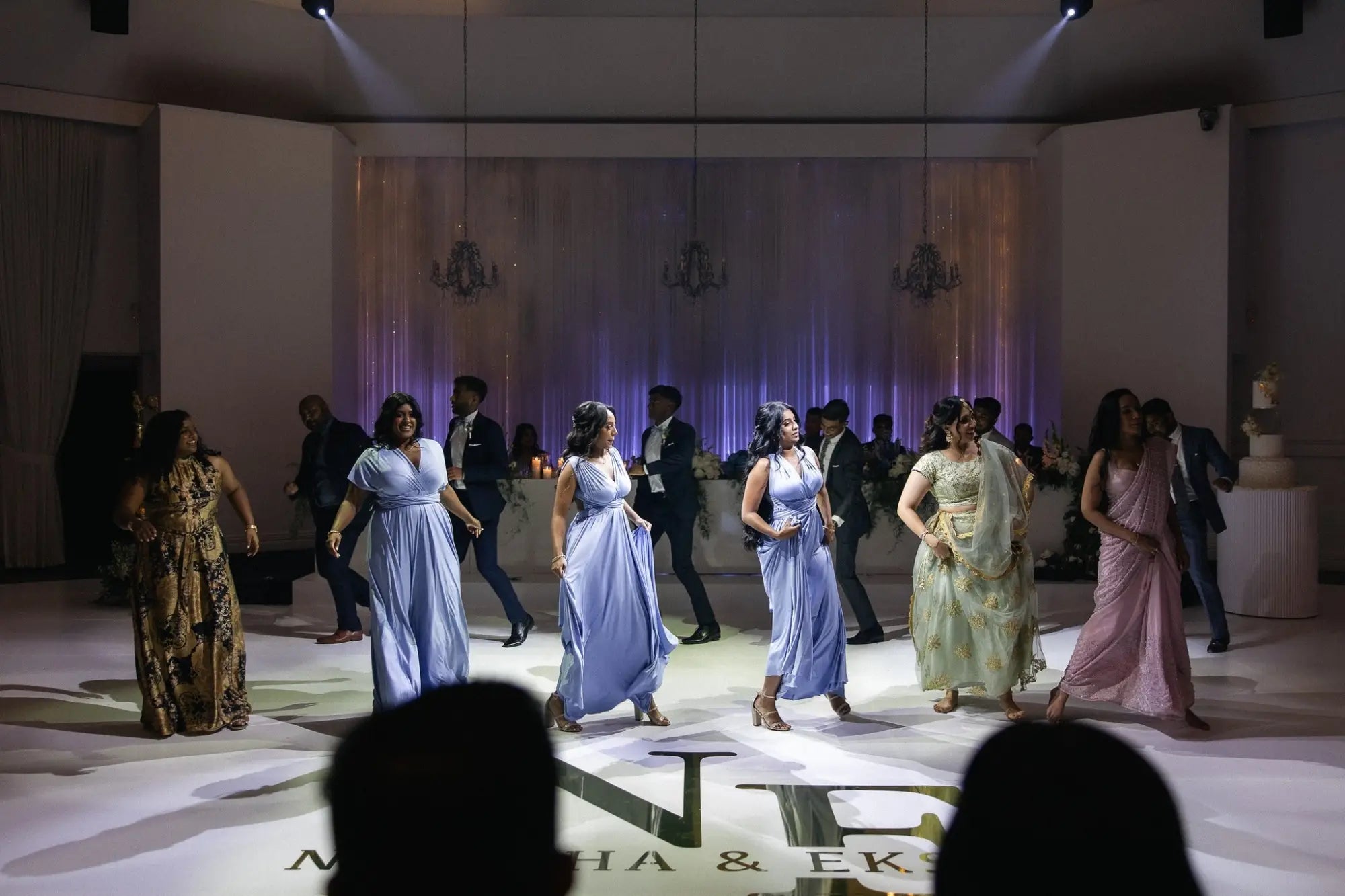 People dancing on white floor wearing infinity dresses in Nirasha and Eksith article