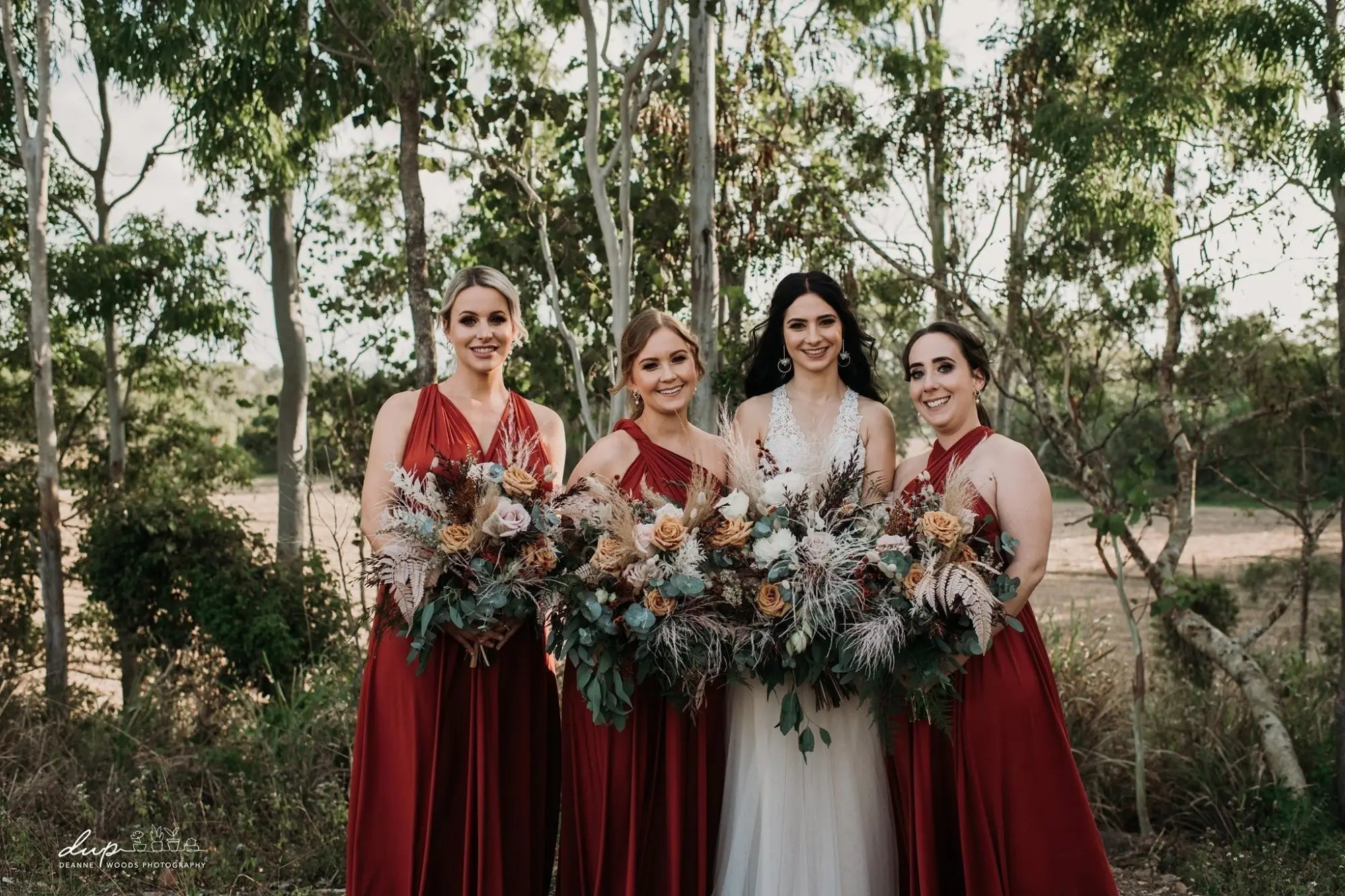 Four women in formal infinity dresses holding bouquets at Sarah and Dean event