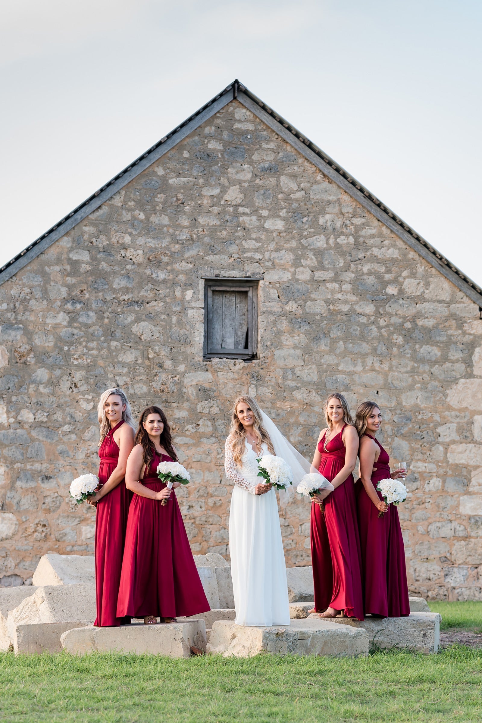 Bride in a white gown with four bridesmaids in maroon multiway bridesmaid infinity gowns