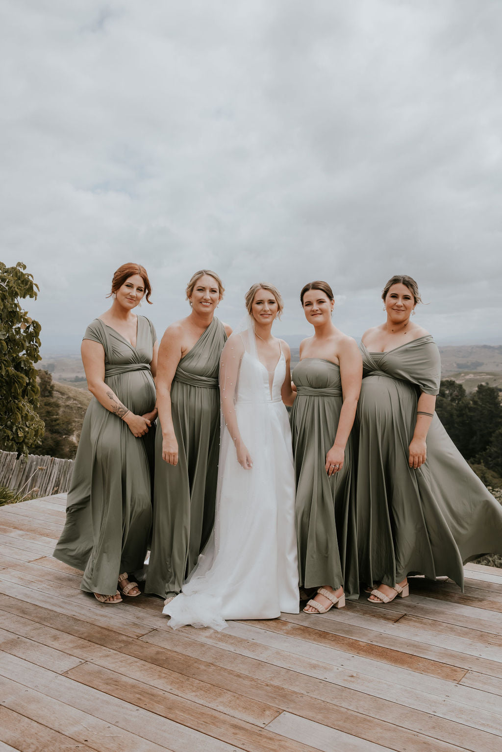 Bride and four bridesmaids in matching olive-green Sage Infinity Gown, a versatile convertible gown