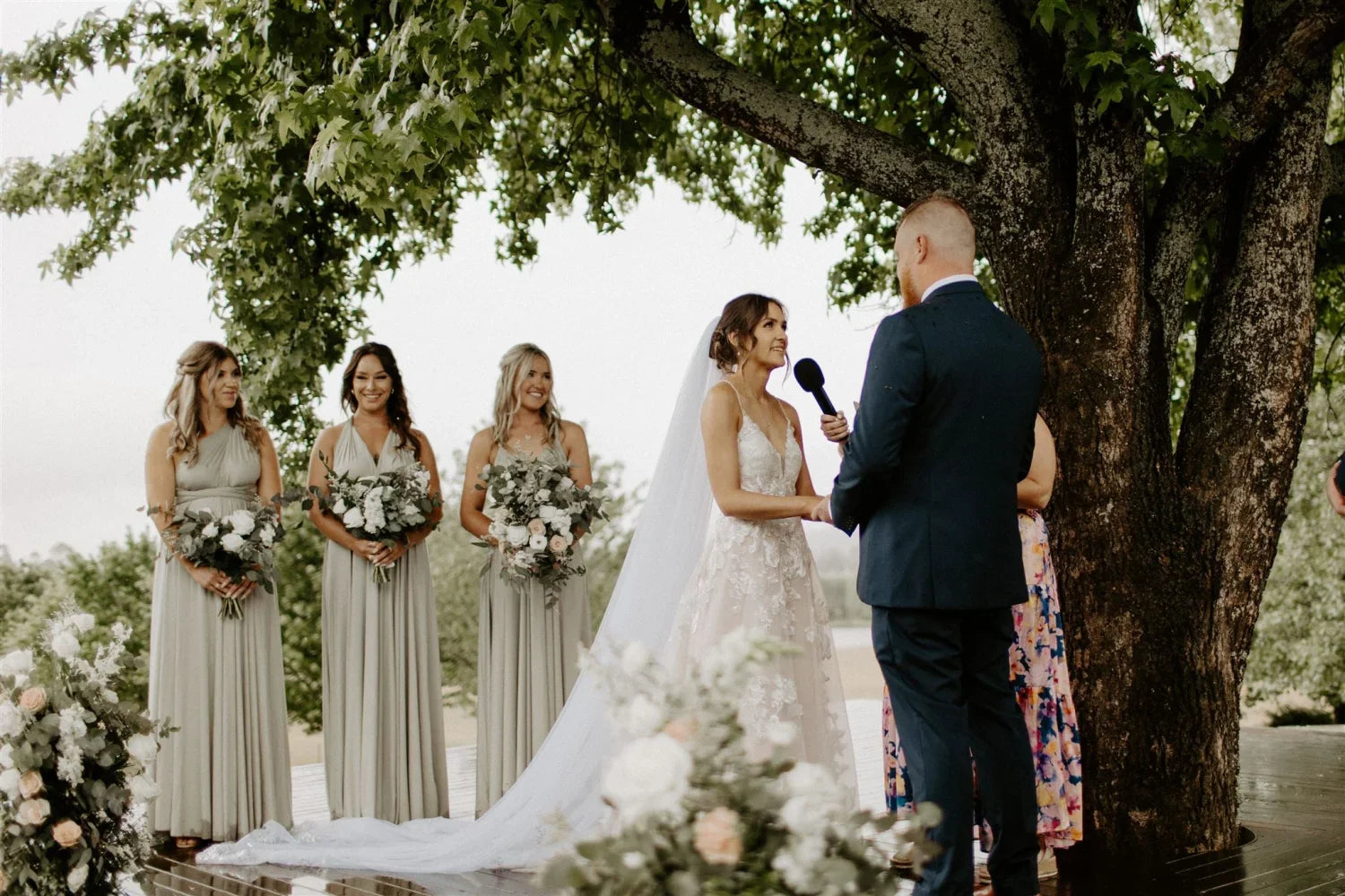 Wedding ceremony featuring a bride, groom, and bridesmaids in Eucalyptus Infinity Gown
