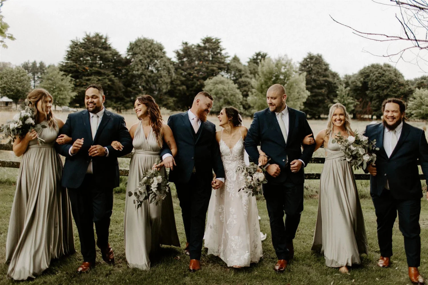 Wedding party in Eucalyptus Infinity Gown and convertible dresses walking arm-in-arm