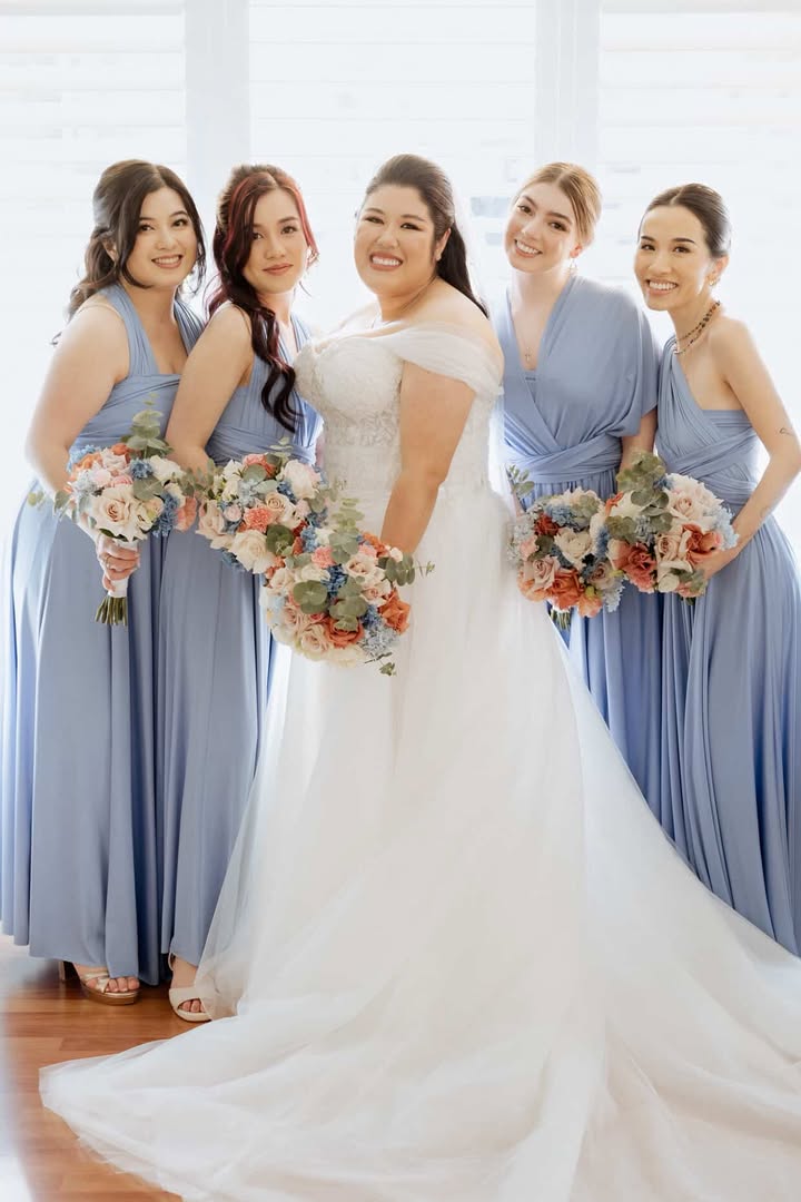 Bride in off-the-shoulder white gown with four dusty blue bridesmaid convertible infinity gowns and bouquets