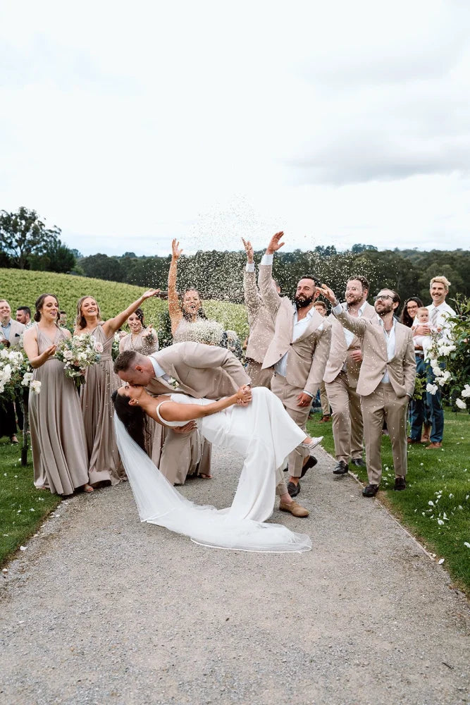 Bridal couple kissing with wedding party and confetti, showcasing Gold Infinity Gown