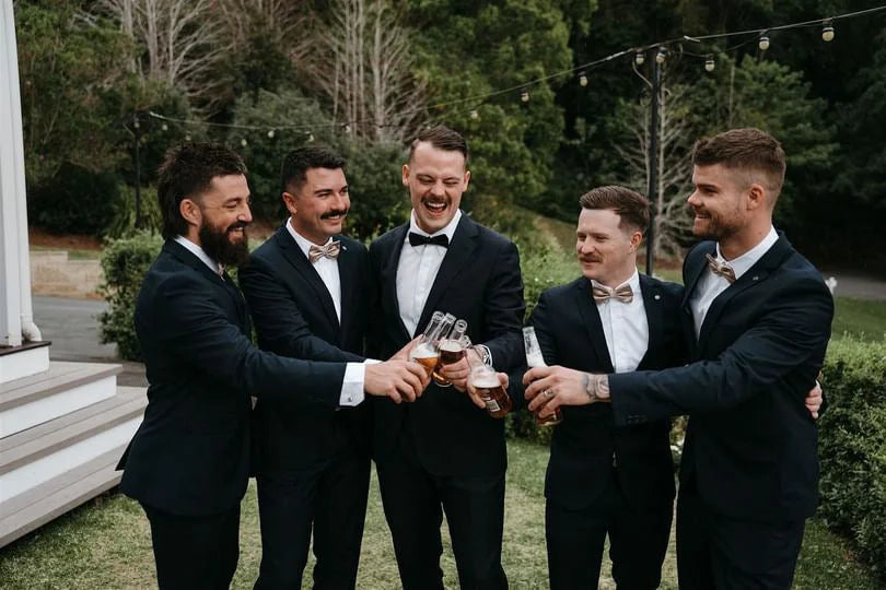 Five men in suits toasting with beer bottles showcasing Gold Infinity Gown, perfect multiway bridesmaid dress Australia
